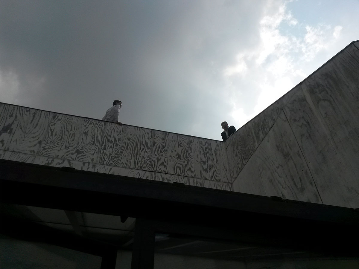 photo à contrejour : deux personnes discutent sur le toit d'un bâtiment